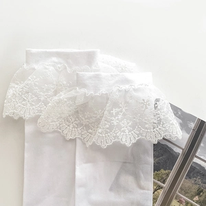 Detailed macro view of white Lolita style socks with ruffled lace trim and floral embroidery