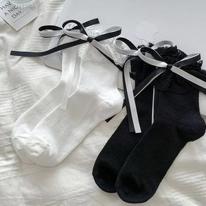 Détail de chaussettes Lolita avec bordure en dentelle et nœuds en satin noir et blanc