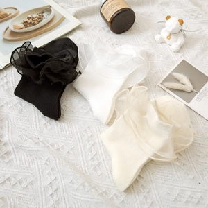 Lot de chaussettes à dentelle Lolita blanches, noires et beige sur un tissu en maille douce