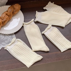 Detail of off-white mesh mid-calf socks with various knit textures and ruffled cuffs