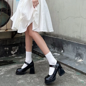 Close-up of black patent leather platform Mary Jane heels with buckles and white socks