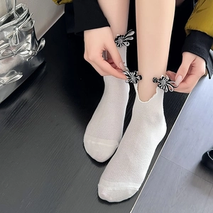 Detailed shot of white mesh socks with black and white frog button flower accents