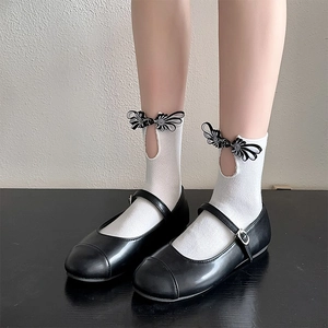 Detail of white honeycomb mesh socks with floral knots paired with black Mary Jane shoes