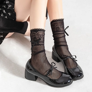 Close-up of Lolita style black lace mesh socks paired with shiny patent leather Mary Janes