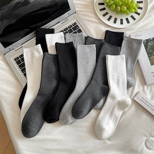 Detailansicht gerippter Baumwollsocken in Grau, Schwarz und Weiß auf weichem Bett