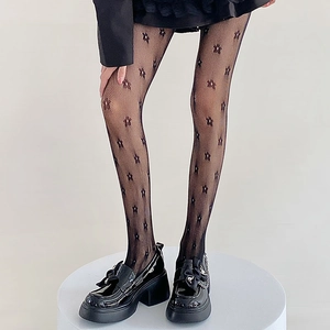 Detail of black hollow mesh tights with floral patterns and matching platform shoes