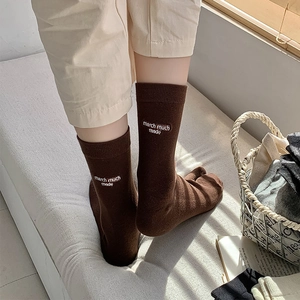 Close-up of brown cotton socks with white letter embroidery on a cozy background