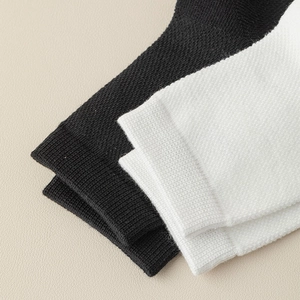 Detailed view of ribbed knit cuffs on white and black cotton socks with elastic texture