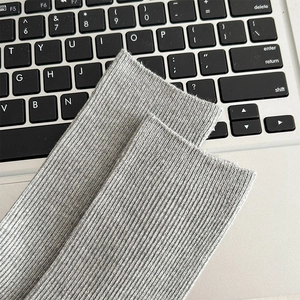 Makroaufnahme der grauen gerippten Baumwollsocken Textur auf einer Tastatur