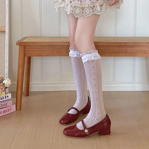 Détail de chaussettes blanches en dentelle à cœur avec des chaussures Mary Jane rouges