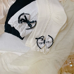 Detail of JK style cable knit socks with contrast bows in black and cream white colors