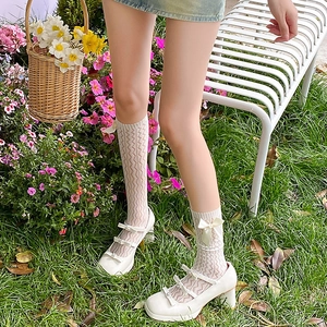 Detailed view of beige lace socks with silk bow and Mary Jane shoes in garden
