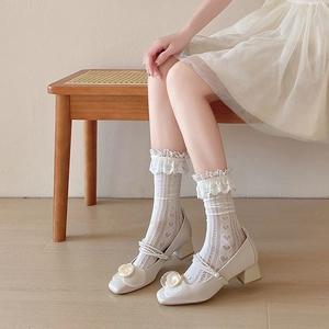 Gros plan de chaussettes hautes en dentelle blanche avec découpes en cœur et nœuds
