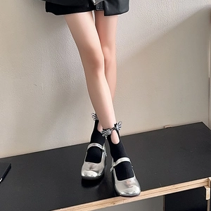 Close-up of silver Mary Jane shoes paired with black bow-knot crew socks on model