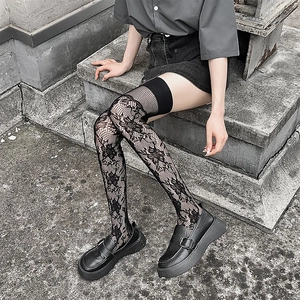 Détail de chaussettes hautes en dentelle noire avec broderie florale et maille filet