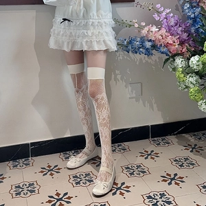 Détail de chaussettes hautes en dentelle blanche avec motifs floraux délicats