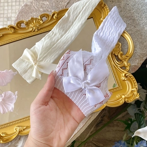 Detail of white hollow lace knit socks featuring elegant oversized satin bows decoration