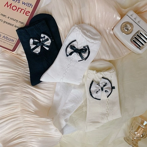 Close-up of cable-knit socks with bow detail in black, white, and beige colors