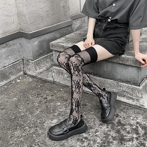 Détail de chaussettes hautes noires avec motifs floraux en dentelle et texture résille