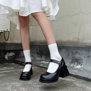 Detail of glossy black patent leather Mary Jane shoes with thick square heels and metal buckle