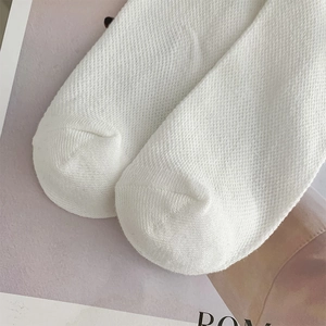 Detail shot of white knitted mesh socks showing fine breathable texture and smooth toe seam