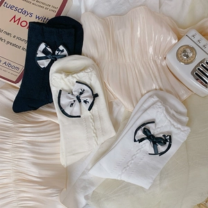Detailed knit texture of cable-knit socks with bow accents in black, white, and cream