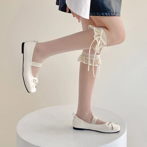 Détail de chaussures Mary Jane blanches avec nœud et chaussettes montantes en dentelle