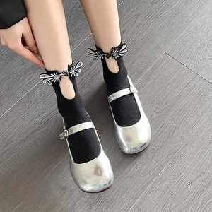 Close-up of silver Mary Jane shoes with black socks featuring a unique teardrop cutout detail