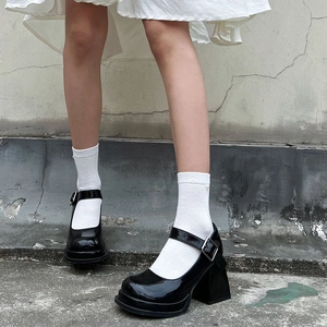 Close-up of black patent leather Mary Jane shoes with thick heels and white socks