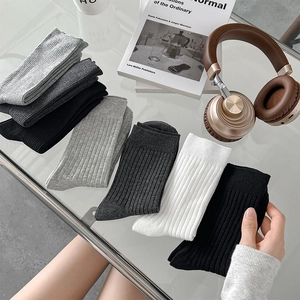 Detail von gerippten Crew-Socken in Grau, Schwarz und Weiß auf einem Glastisch