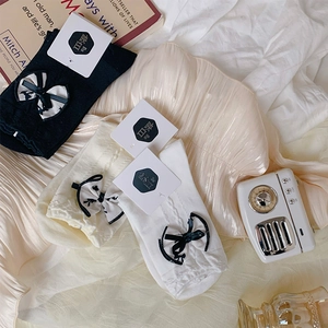 Three pairs of knit socks with bow accents in black, cream, and white with cable texture