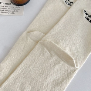 Macro detail of ribbed off-white socks featuring black 'march made' letter embroidery