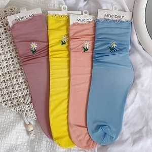 Detailed view of daisy embroidery and ruffled cuffs on four pairs of sheer mesh socks