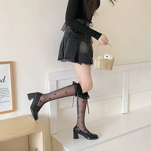 Detail of sheer black calf socks with heart pattern, lace trim, and bow tie accents