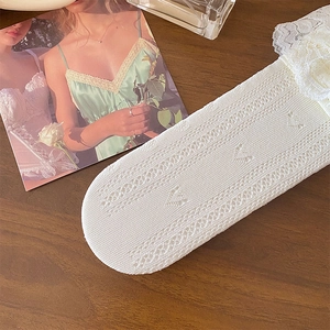 Détails de chaussettes en dentelle blanche avec motifs ajourés en cœur et maille tricotée
