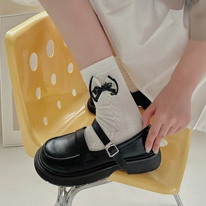 White lace patterned socks with black bows paired with platform Mary Jane shoes