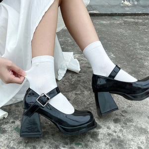 Detail of black patent leather Mary Jane platform shoes worn with white mesh socks