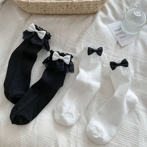 Détail de chaussettes Lolita blanches et noires avec dentelle double et nœuds satin