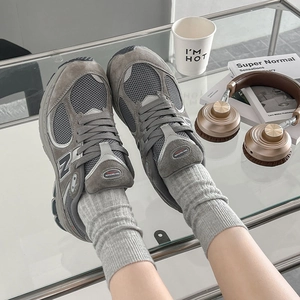 Detailaufnahme von dunkelgrauen Mesh-Sneakern mit passenden Strick-Crew-Socken auf Glastisch