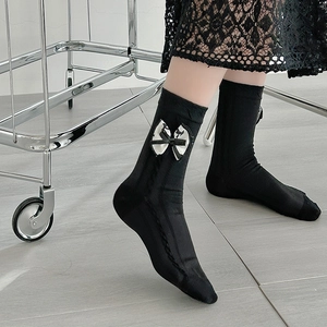 Detail of black knit crew sock with decorative bow accent and ribbed cuff styling
