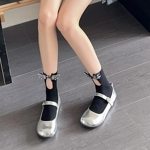 Detail of silver Mary Jane shoes with black decorative cutout socks and metal fasteners