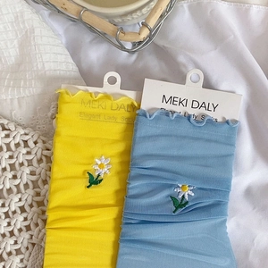 Detail of daisy embroidery on breathable mesh socks with ruffled cuffs in yellow and blue