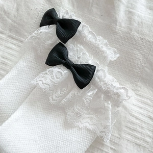 Détail de chaussettes Lolita blanches avec dentelle délicate et nœuds en satin noir décor