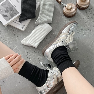 Detail von gerippten Crew-Socken in Grau, Schwarz und Weiß kombiniert mit Turnschuhen