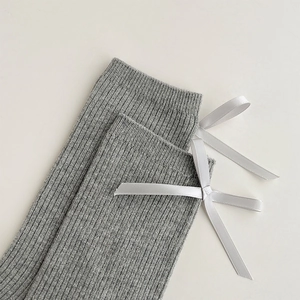 Detailed close-up of grey ribbed socks with white satin bow decoration in ballet style