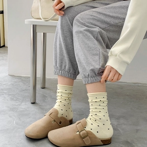Socken mit Punkten im japanischen Stil und Pantoletten aus Kamel-Wildleder auf grauem Boden