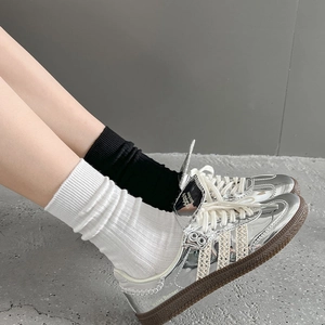 Silberne Metallic-Sneaker mit Gummisohle, kombiniert mit schwarzen und weißen Socken
