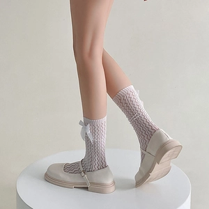 Detail of white wave pattern mid-calf socks with delicate silk bow and Mary Jane shoes