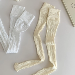 Détail de chaussettes hautes en dentelle blanche et crème avec motifs floraux ajourés