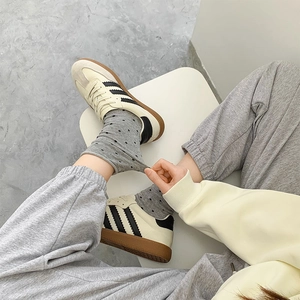 Nahaufnahme von Retro-Sneakern mit schwarzen Streifen und Gummisohle auf gepunkteten Socken